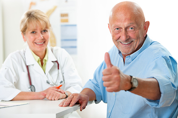 Image Mann glücklich mit Daumen hoch sitzt vor Ärztin